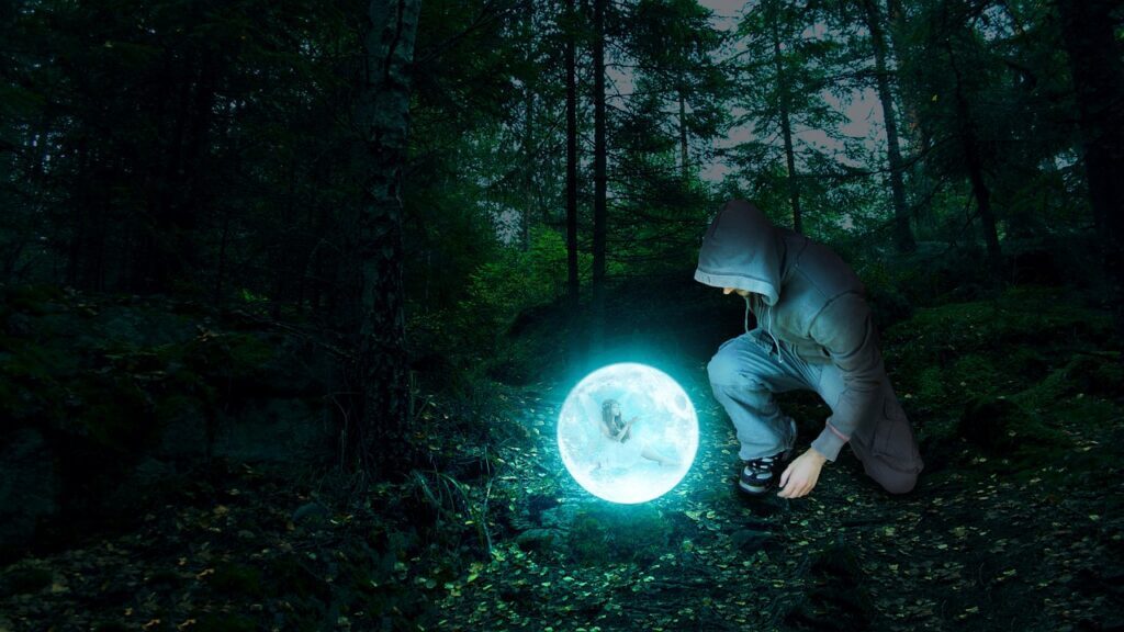 a man staring at a bright ball sitting inside a dark forest